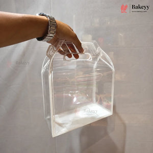 A clear plastic storage box with integrated handles, held by a person's hand against a light gray fabric backdrop.
