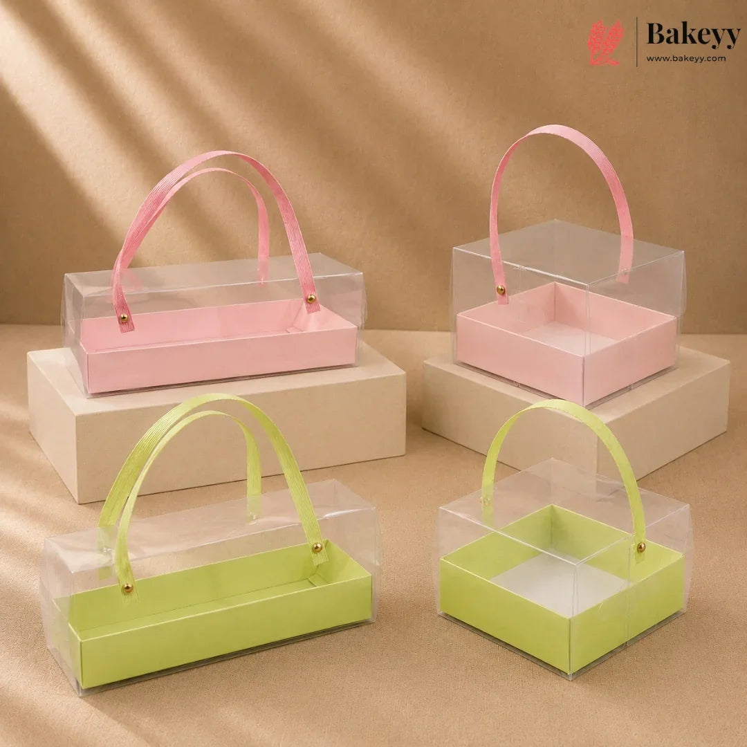 Clear gift boxes with pink and green handles on beige platforms, featuring the Bakeyy brand.