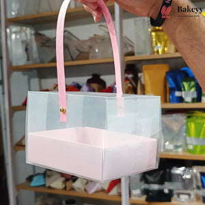 Clear box with pink interior and handle held by a person in a store setting