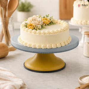 Decorative cake on a yellow stand with flowers in a kitchen setting