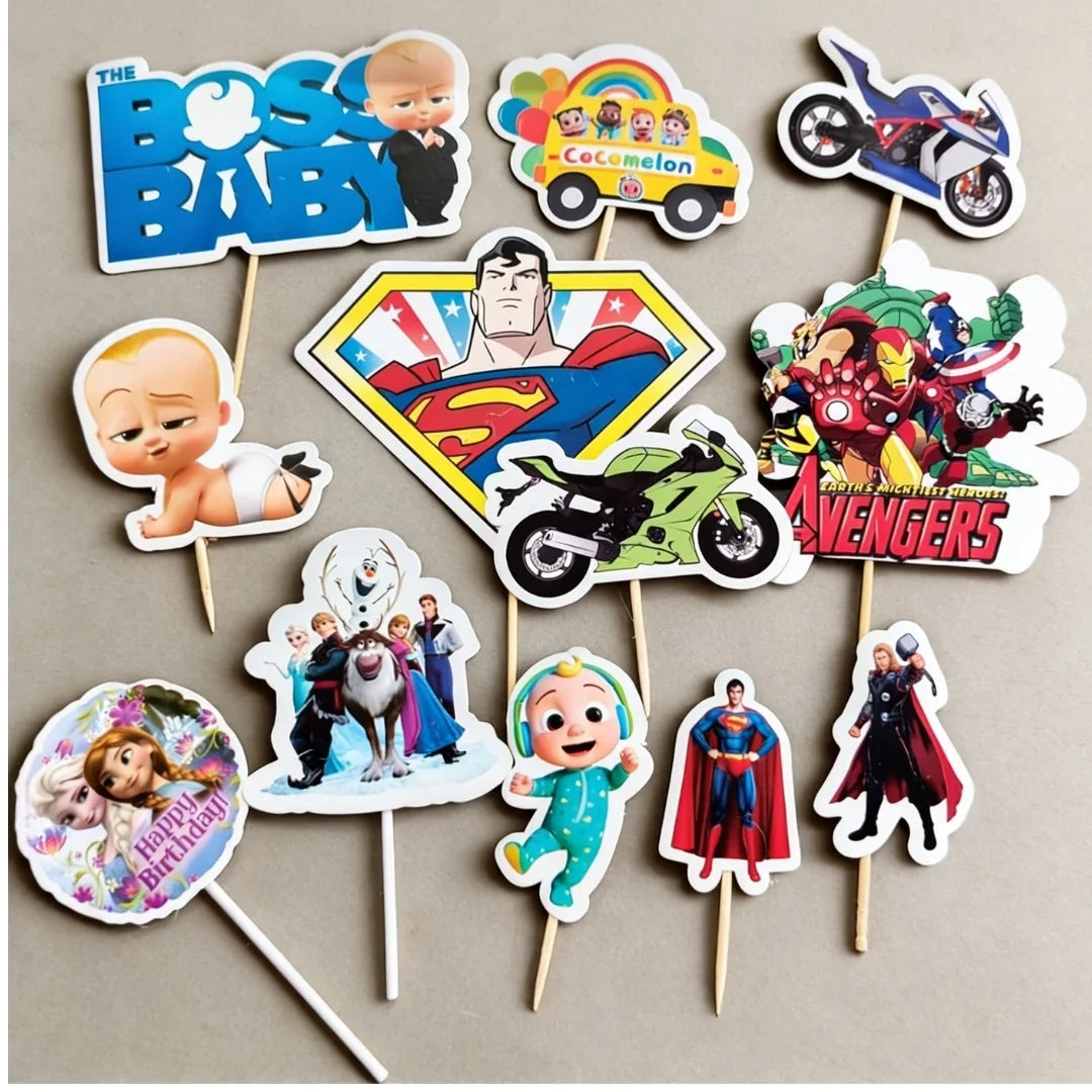 A set of cartoon and character-themed party cupcake toppers on wooden sticks, featuring characters and logos including The Boss Baby, Cocomico, Superman, Avengers, Baby Einstein, Frozen, and Marvel.