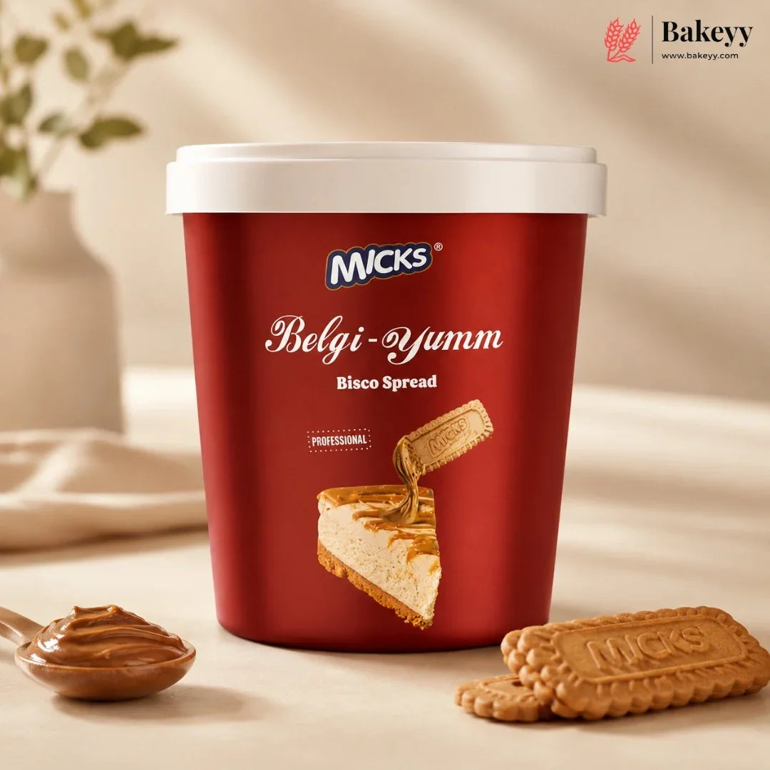 A red tub of Micks Belgi-Yumm Bisco Spread with a white lid, styled on a beige surface with a spoonful of spread and two biscuit cookies in the foreground.