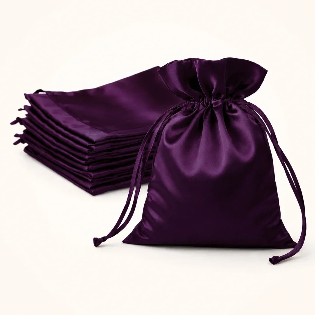 Stack of purple satin drawstring bags on a white background