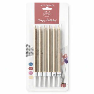 Six gold birthday candle sticks in a blister pack with a pink 'Happy Birthday' header card. The candles have white tips and are shown on a clean white background.
