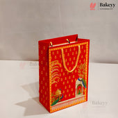 A red and gold decorative gift bag with peacock and architectural illustrations, standing on a white surface against a light gray background. Bakeyy branding is visible in the top right and as faint watermarks.