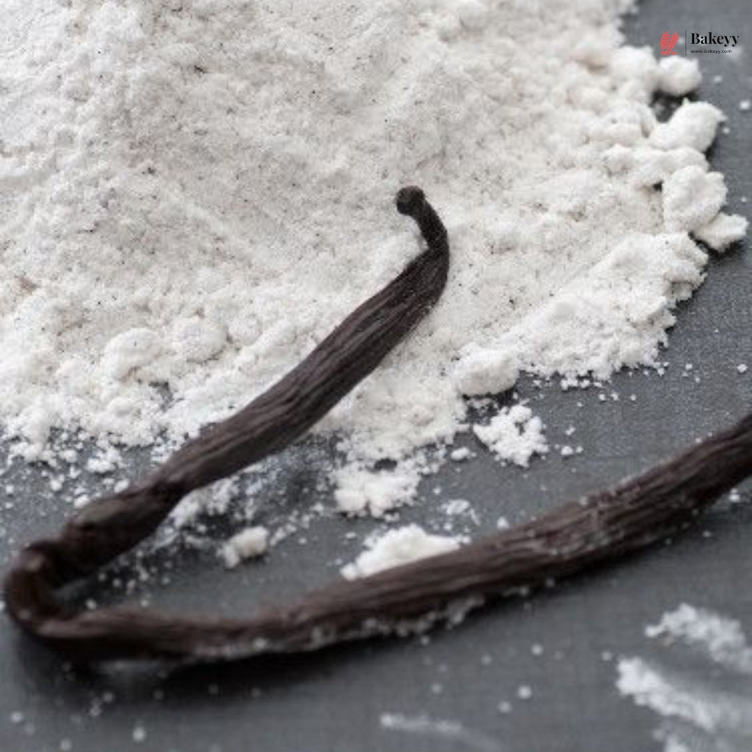 Vanilla beans on a surface with a close-up of vanilla powder