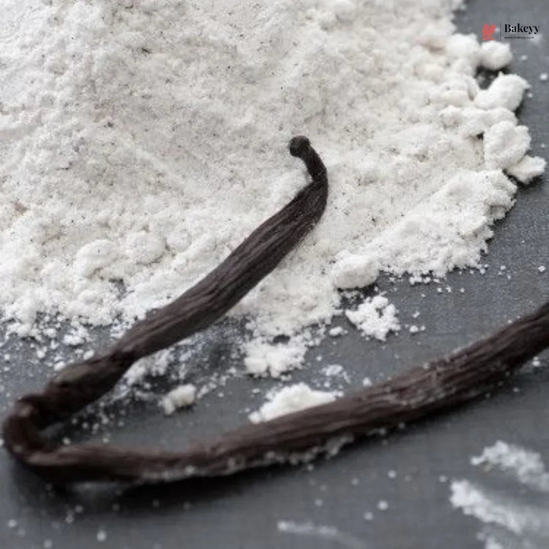 Vanilla beans on a surface with a close-up of vanilla powder