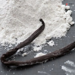 Vanilla beans on a surface with a close-up of vanilla powder