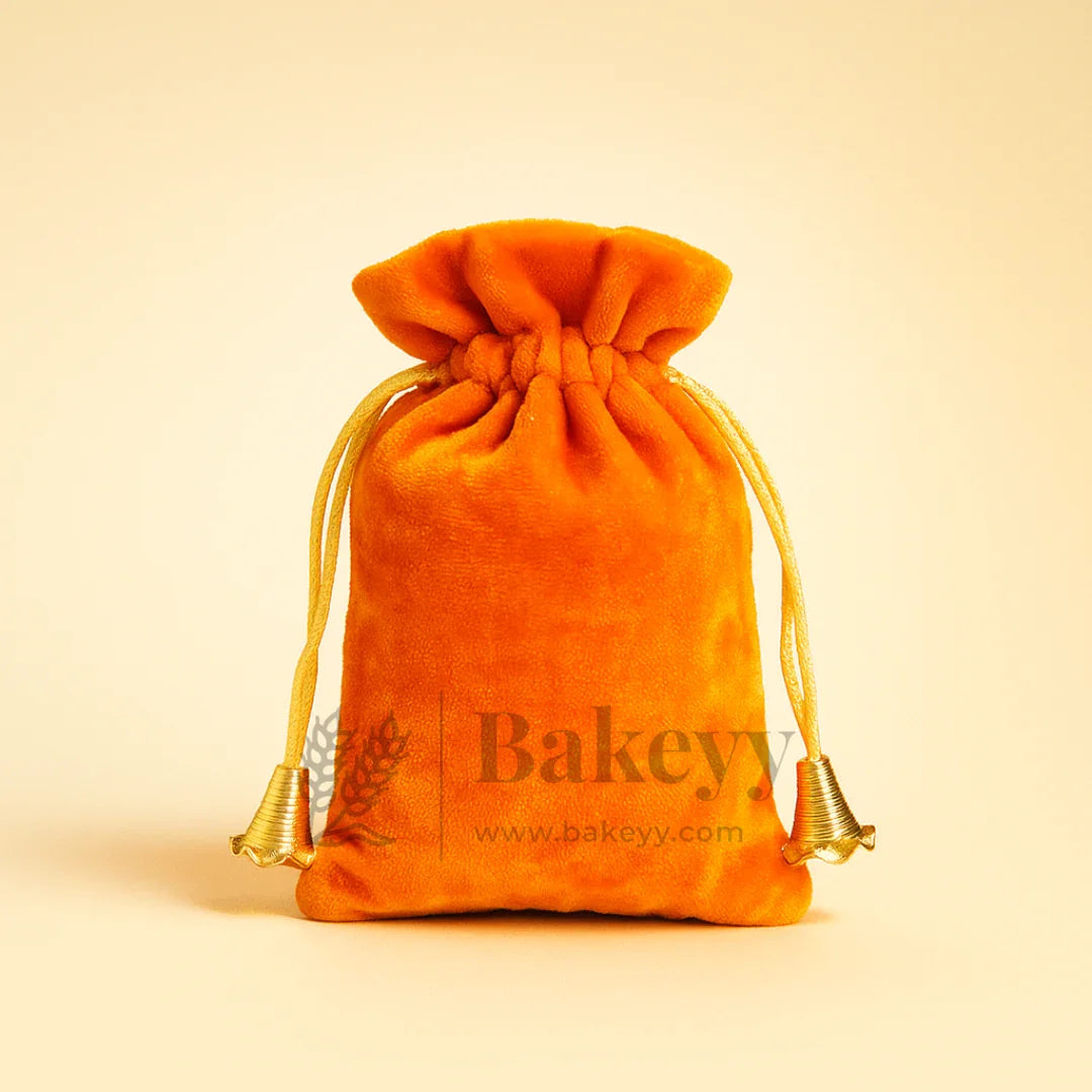 Orange velvet potli gift bag with gold drawstrings from Bakeyy.com on plain background