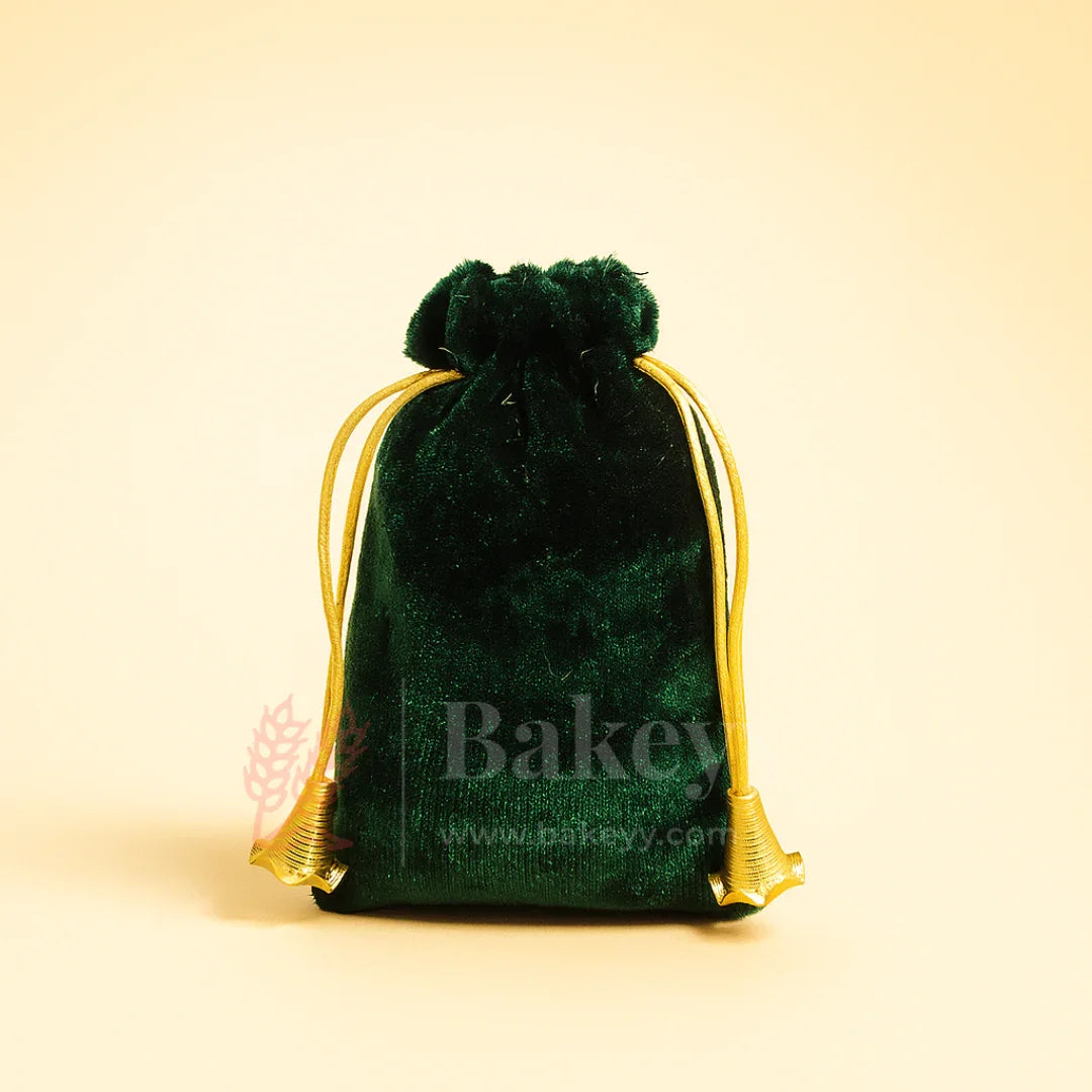Green velvet potli gift bag with golden drawstring on light background, Bakeyy packaging