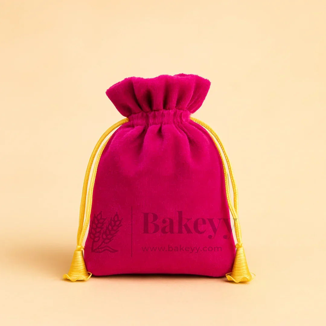 Pink velvet potli gift bag with yellow drawstrings from Bakeyy.com on beige background
