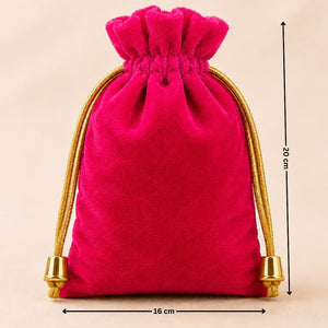 Pink velvet drawstring bag with gold tassels and measurements on a beige background