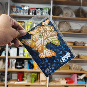 Hand holding a card with butterfly design in front of a store shelf.