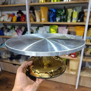 Metallic cake stand held in a hand with shelves of products in the background