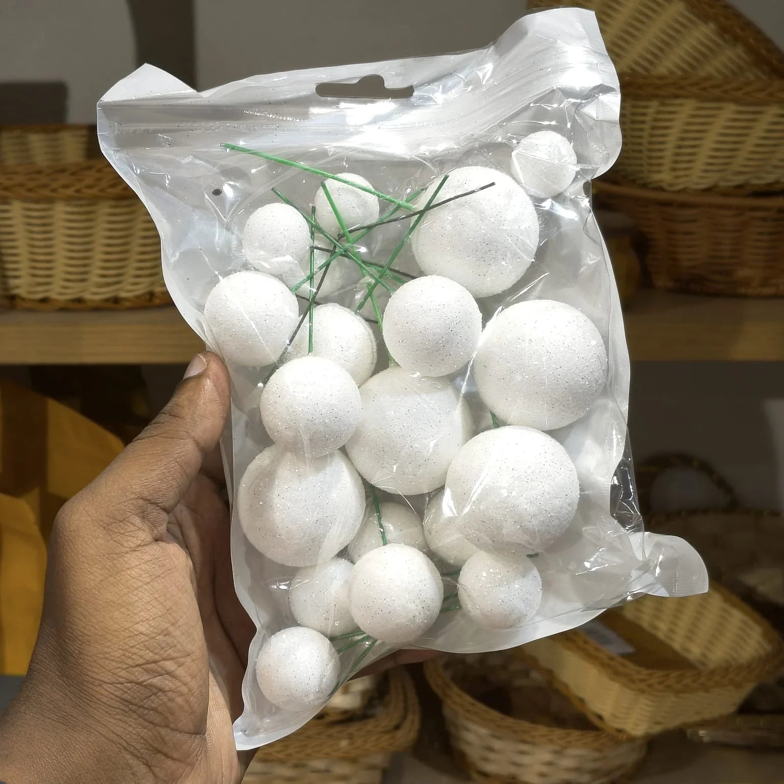 Hand holding a clear plastic bag filled with white round objects against a blurred background.