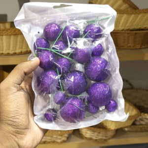 Hand holding a package of purple decorative balls with wicker baskets in the background