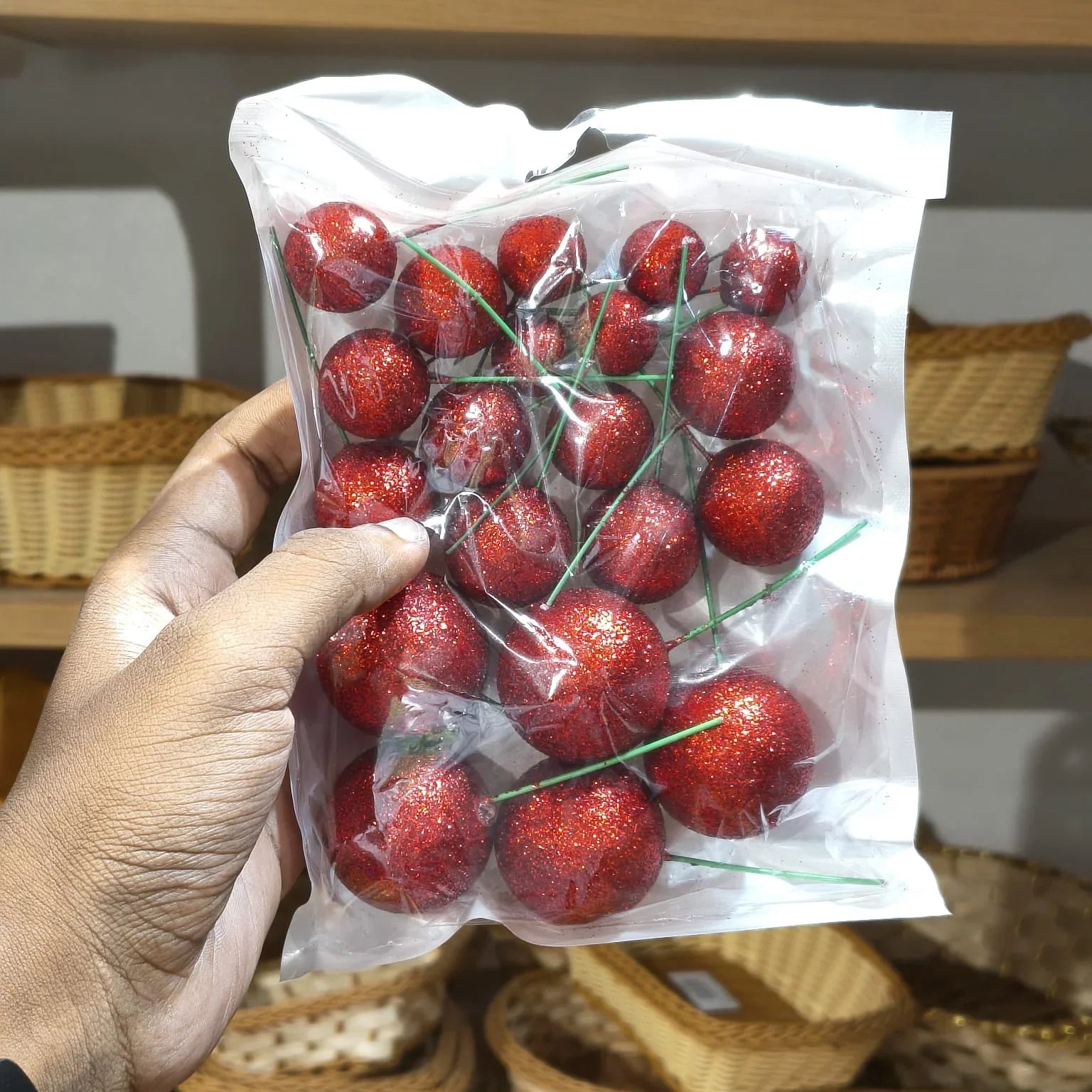 Hand holding a package of red cherries with a blurred background