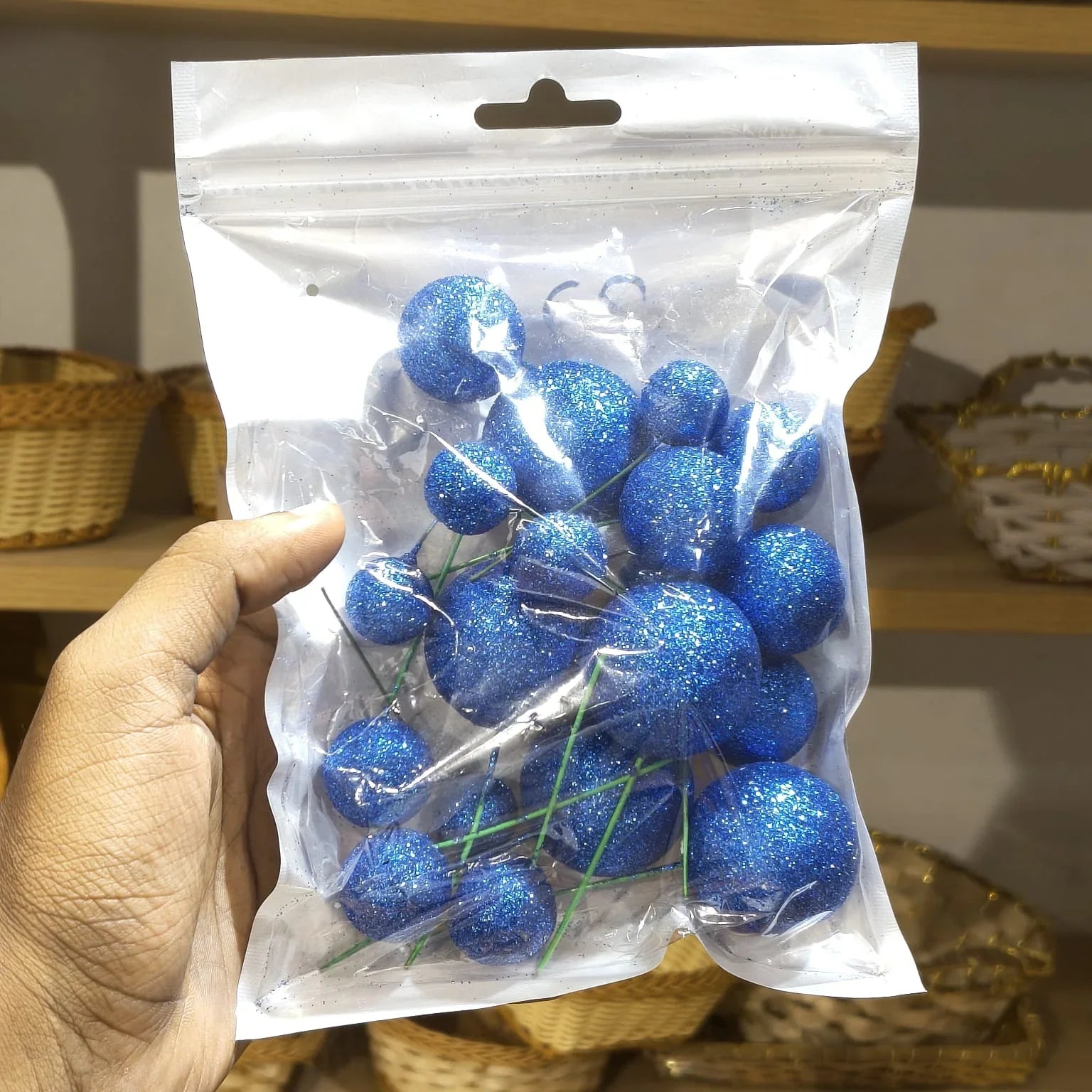 Hand holding a package of blue decorative balls with a blurred background