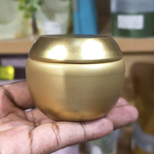 Gold-colored container held in a hand with a blurred background