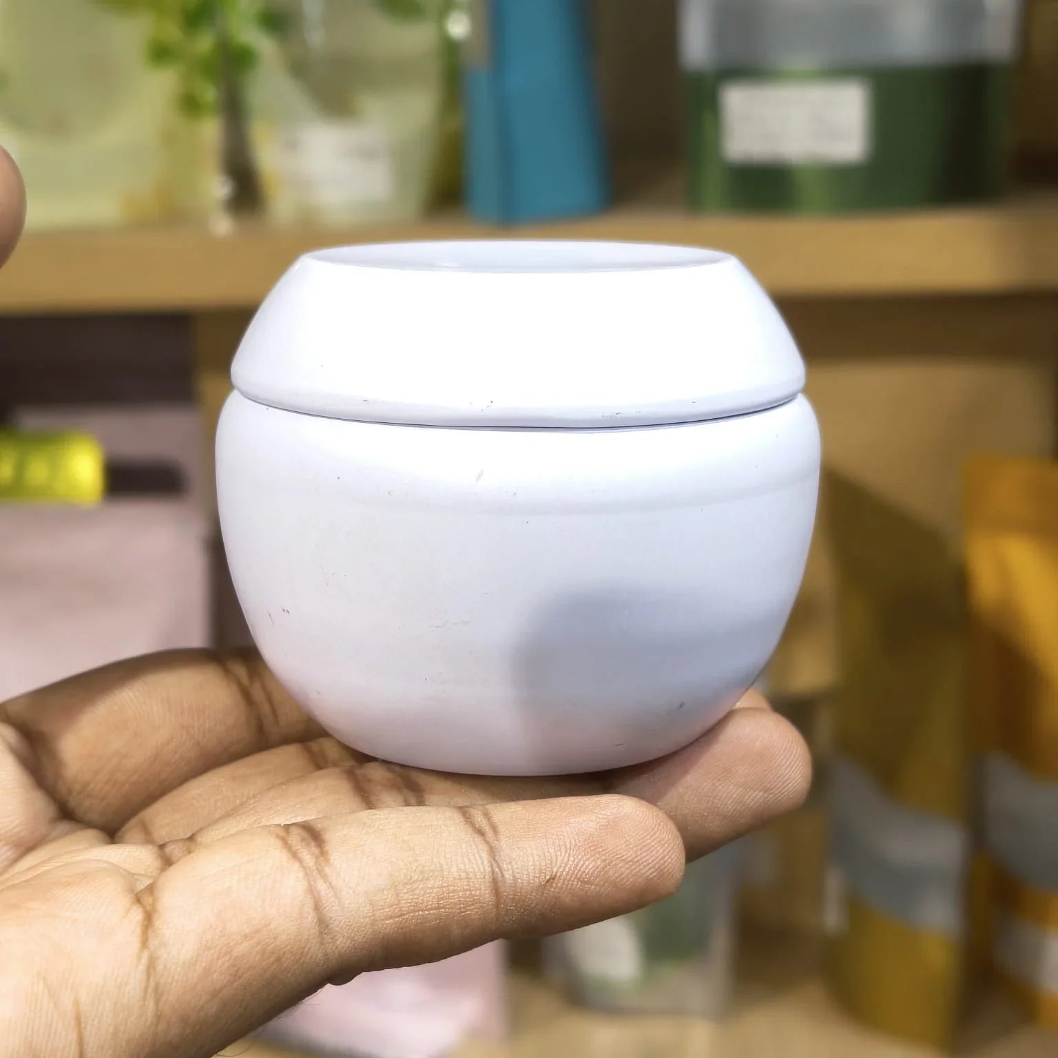 White ceramic cup held in a hand with a blurred background