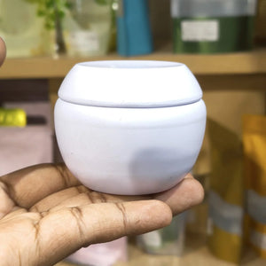 White ceramic cup held in a hand with a blurred background