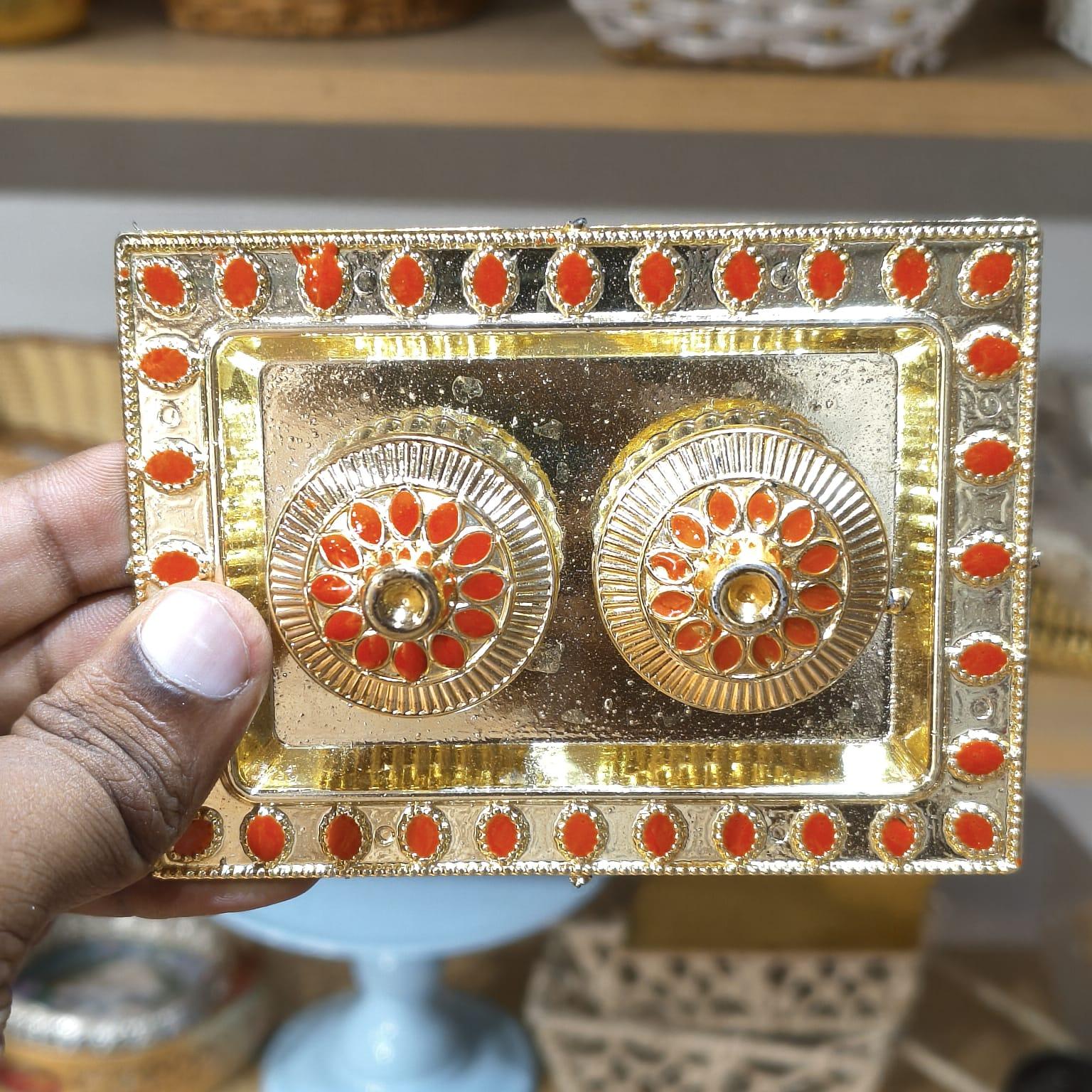 Decorative gold and red rectangular box held by a hand with a blurred background