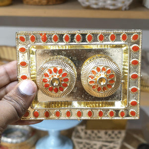 Decorative gold and red rectangular box held by a hand with a blurred background