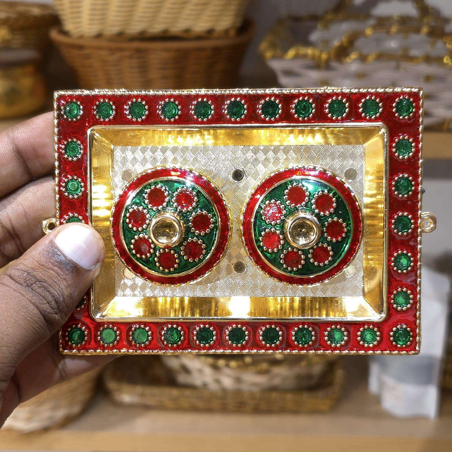 Decorative red and gold box with green accents held by a hand.