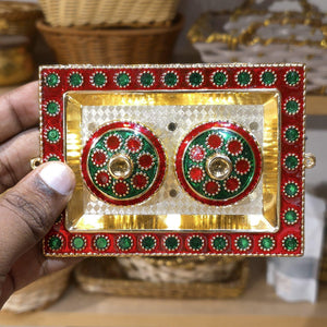 Decorative red and gold box with green accents held by a hand.
