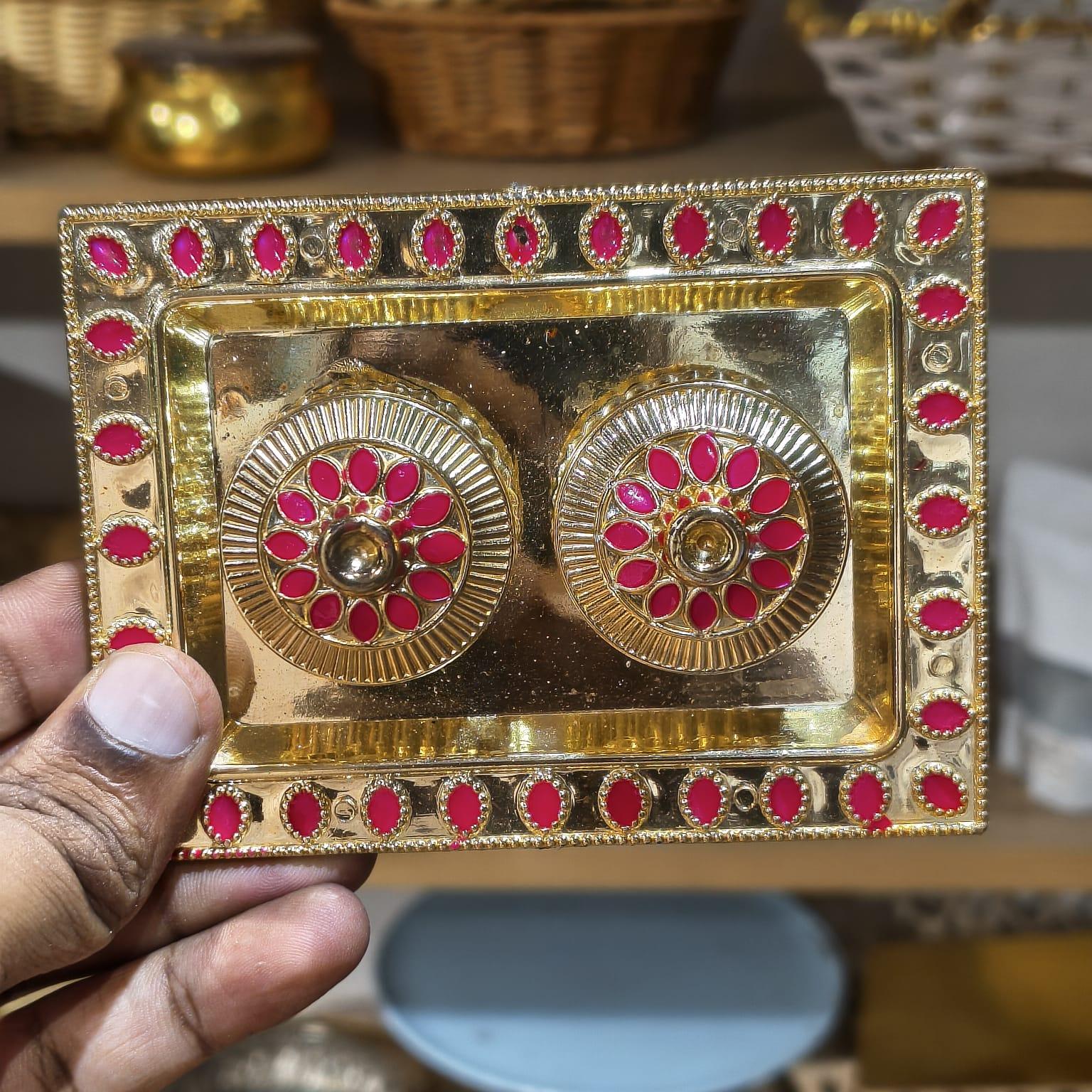 Decorative gold and red rectangular box held by a hand with blurred background