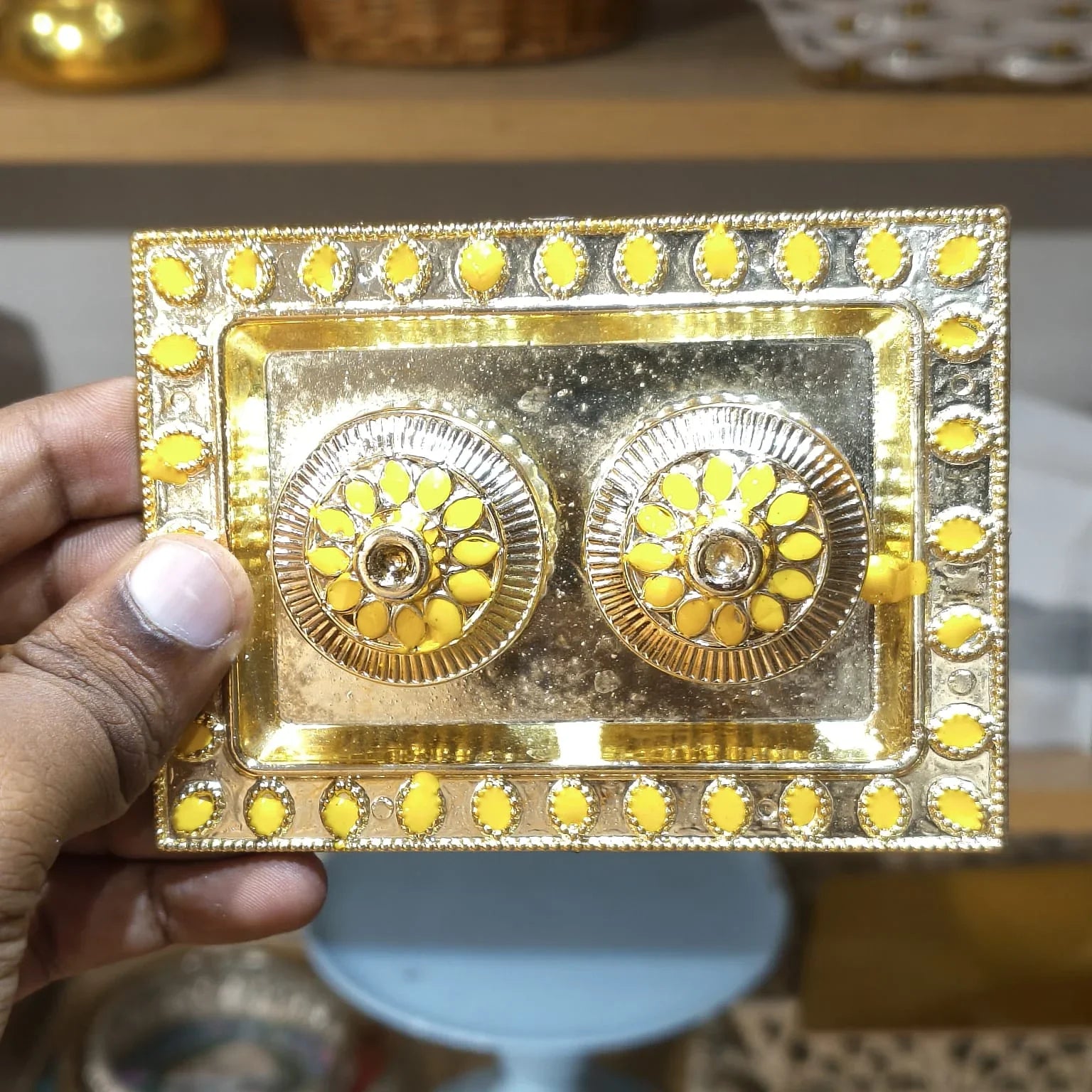 Decorative gold and yellow box held by a hand with a blurred background
