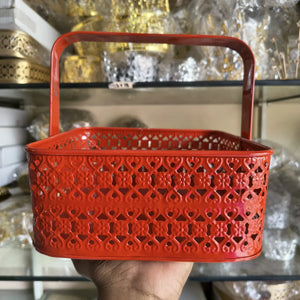 Red perforated basket held in a hand with a blurred background