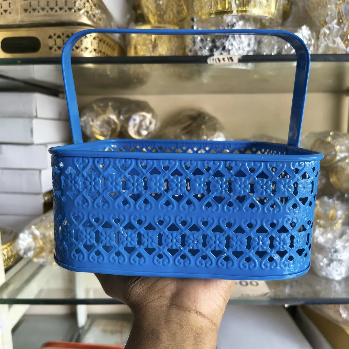 Blue perforated basket held in front of a store shelf with decorative items.