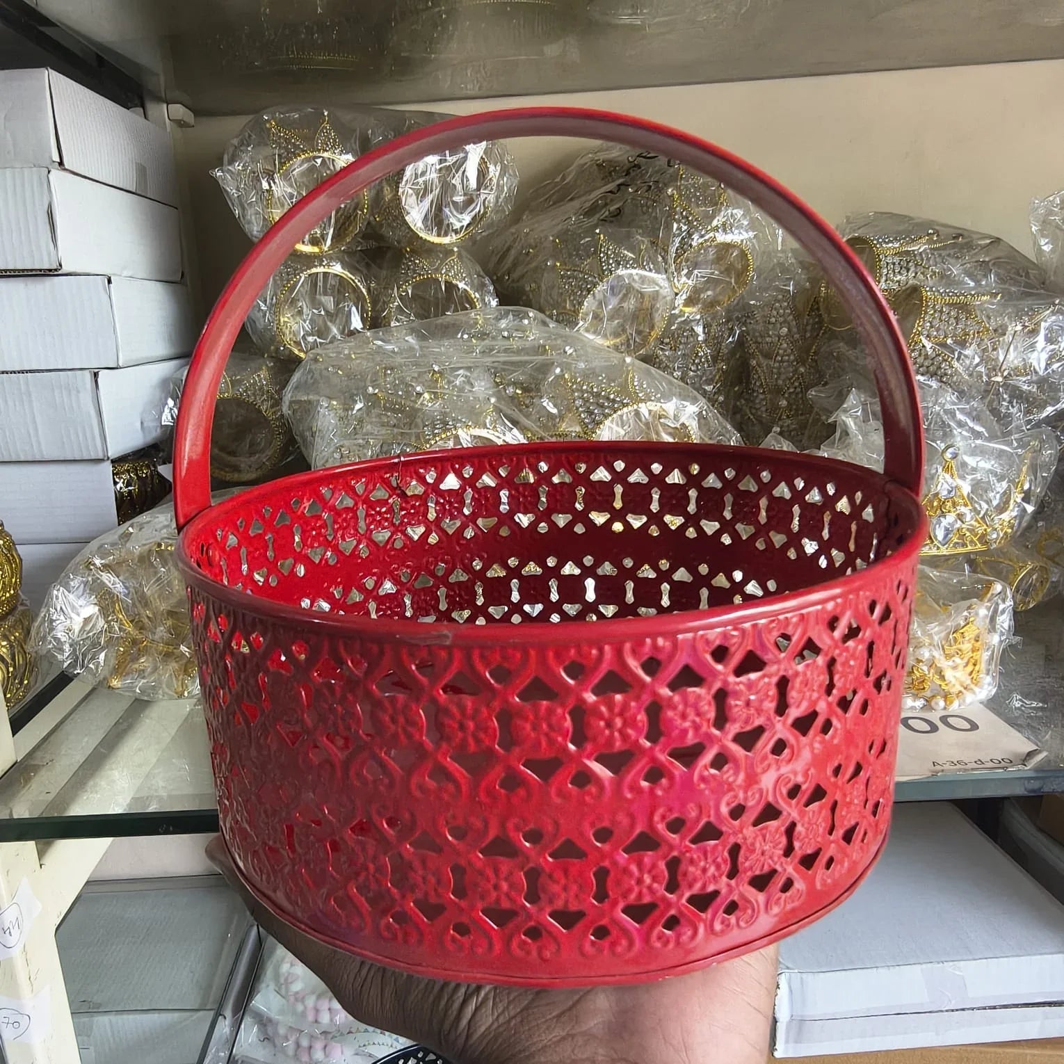 Red decorative basket with intricate patterns held in front of packaged items.