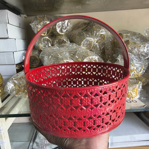 Red decorative basket with intricate patterns held in front of packaged items.