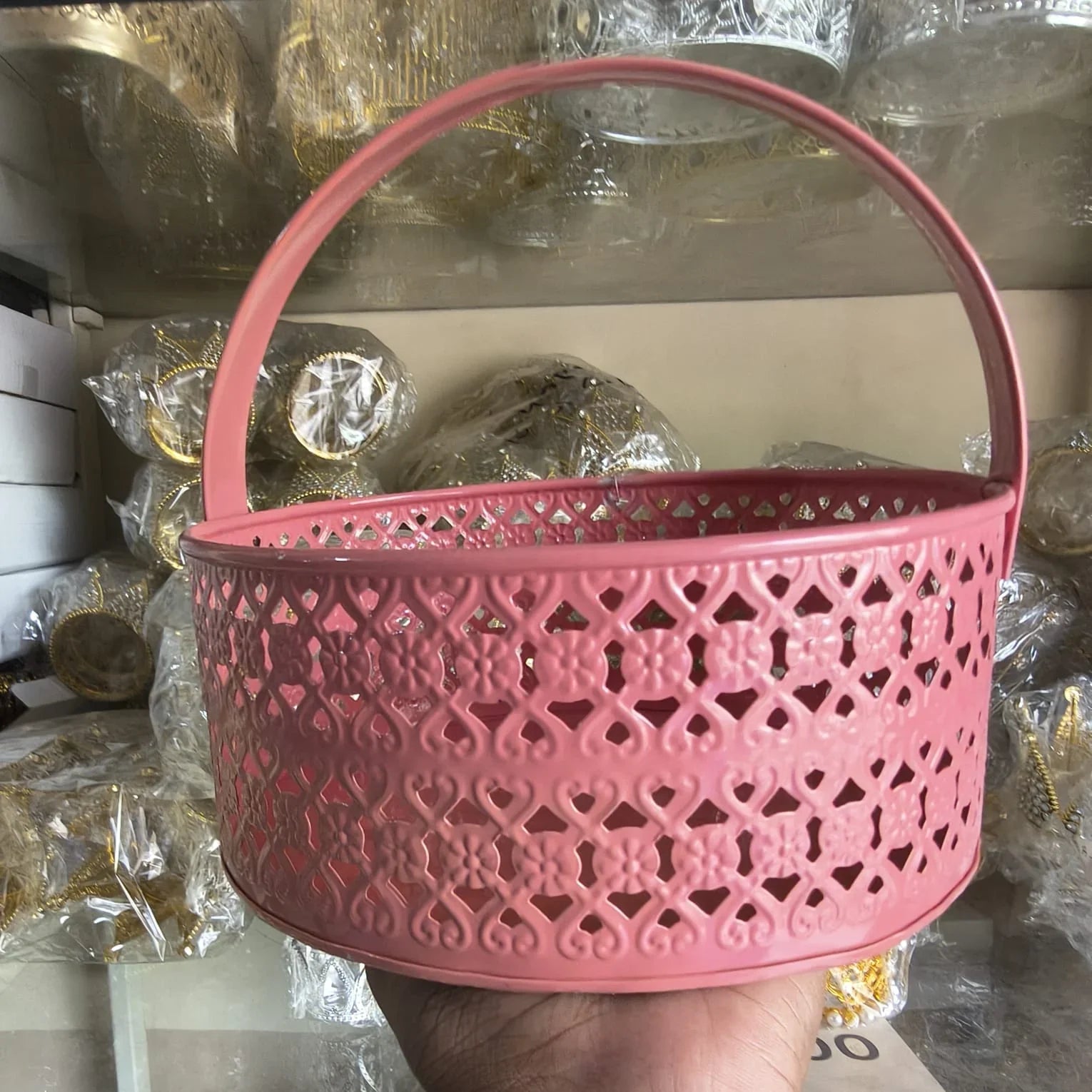 Pink decorative basket with intricate patterns held in front of a blurred background
