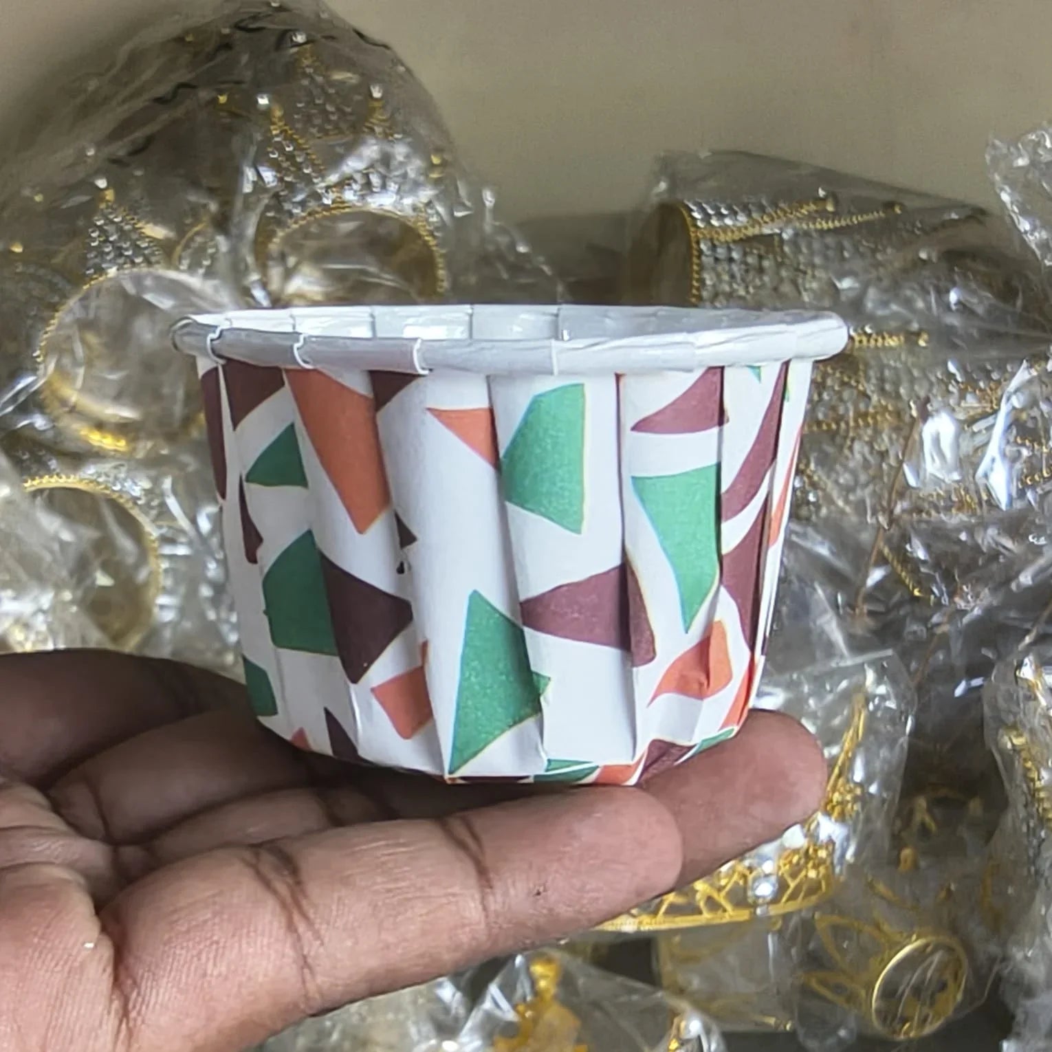 Small patterned container held in a hand with a blurred background