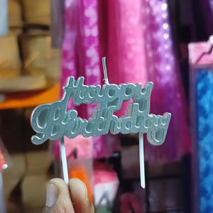 Metallic 'Happy Birthday' cake topper held in front of a colorful background