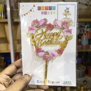 Happy Birthday cake topper packaging held by a hand with a blurred background