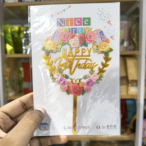 Hand holding a birthday cake topper packaging with floral design and text.