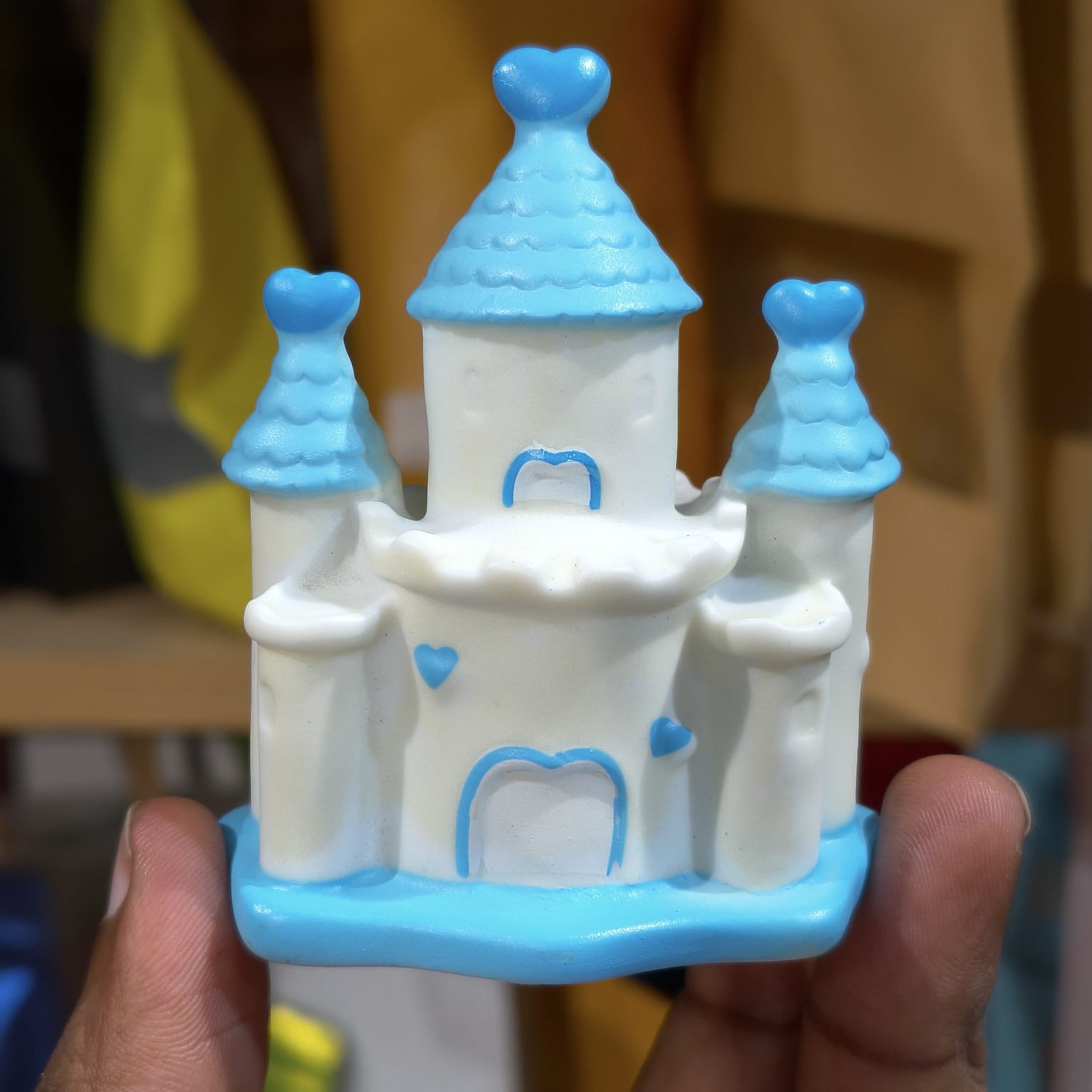 Toy castle with blue roofs held in a hand against a blurred background