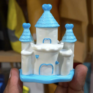 Toy castle with blue roofs held in a hand against a blurred background
