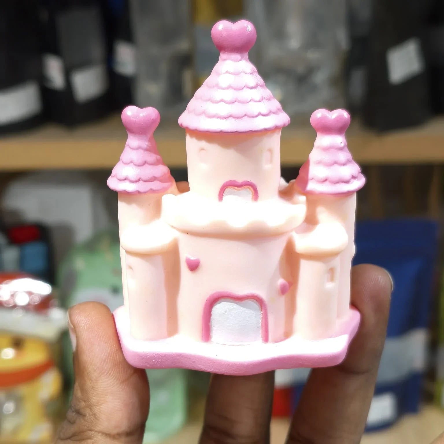 Pink toy castle held in a hand with a blurred background