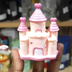 Pink toy castle held in a hand with a blurred background