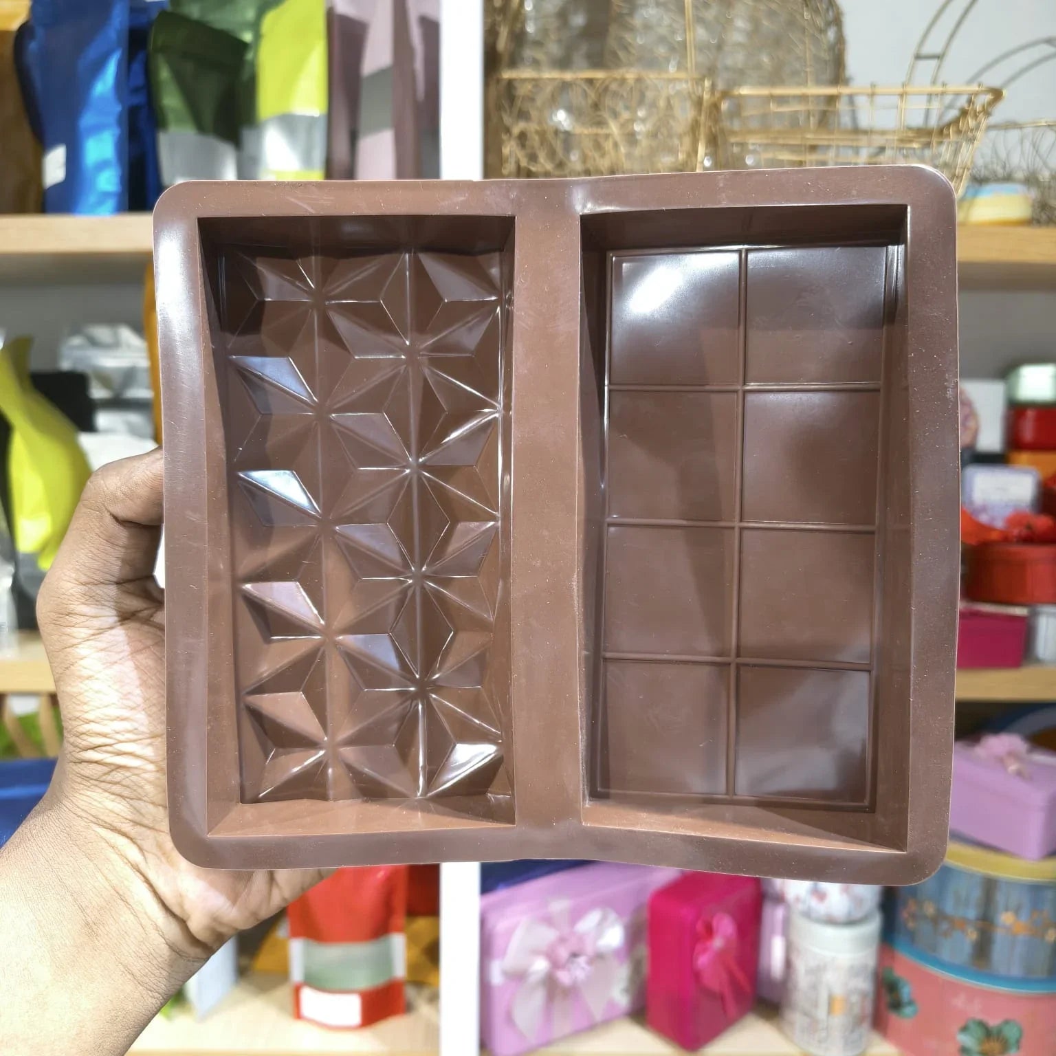 Bronze-colored chocolate mold held by a hand with a blurred background