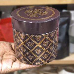 Decorative purple container with gold patterns held by a hand against a blurred background