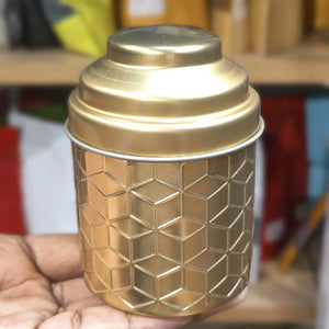 Gold textured container held in a hand with a blurred background