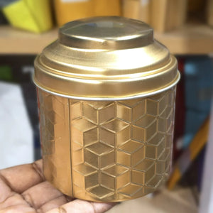 Gold textured container held in a hand with a blurred background