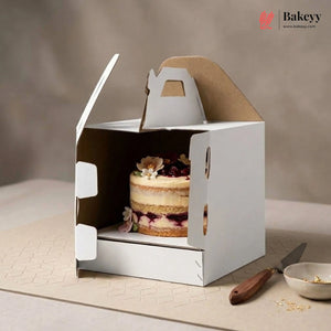 White cake box with a partially eaten cake inside, on a neutral background with 'Bakeyy' branding.