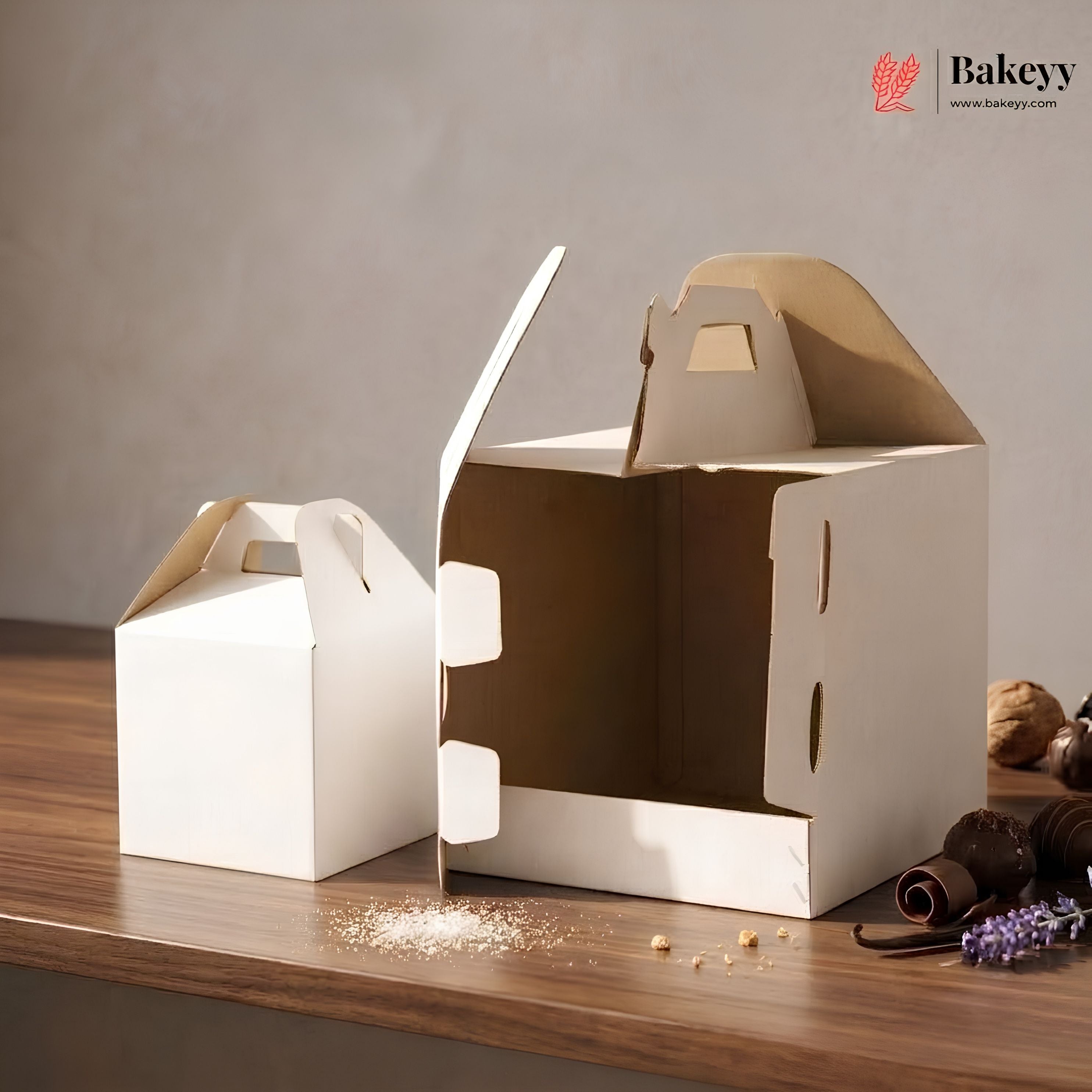 Two cardboard boxes with handles on a wooden surface, featuring the Bakeyy brand.